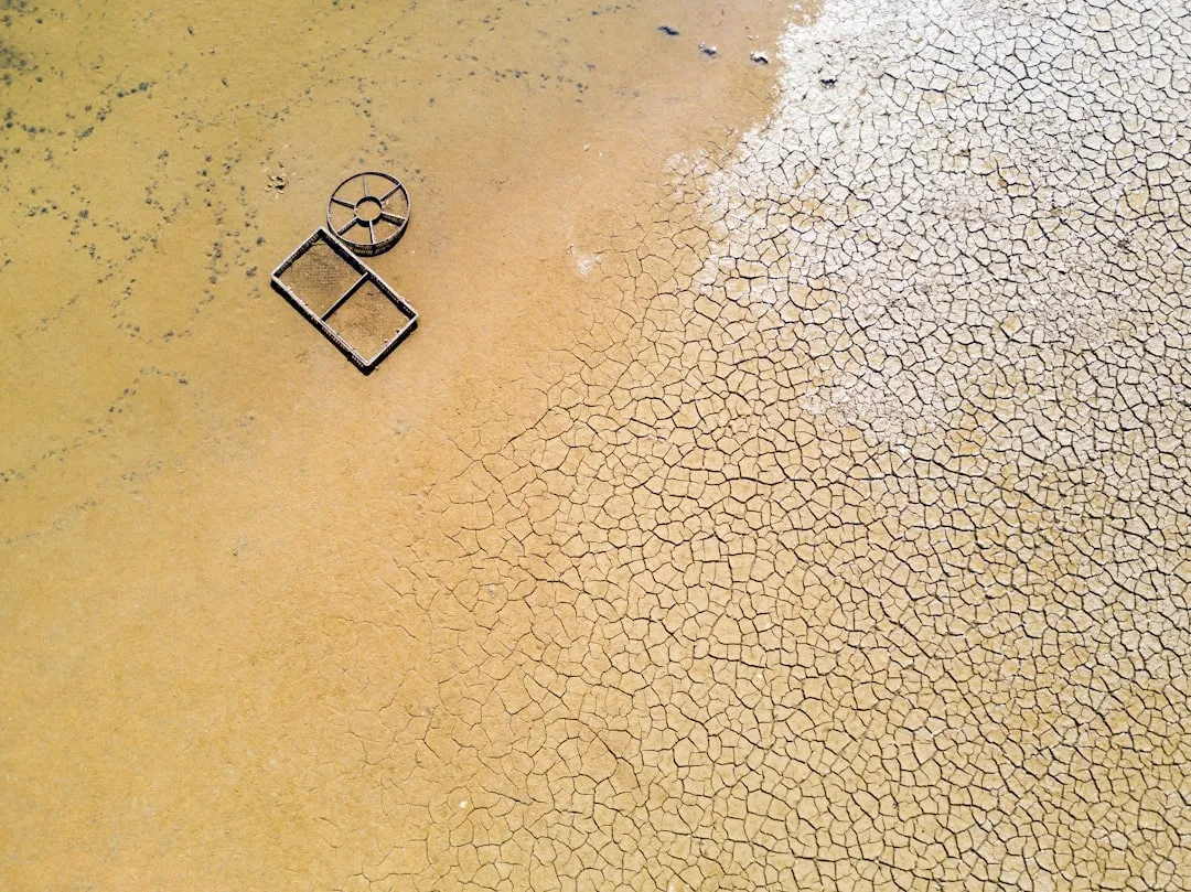 an aerial view of a beach with a square shaped object in the sand - Photo par Olivier Mesnage sur Unsplash