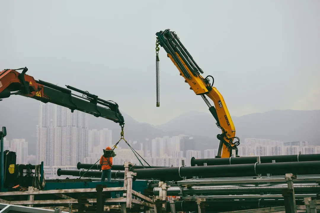 A crane is lifting pipes into the air - Photo par Raymond Yeung sur Unsplash