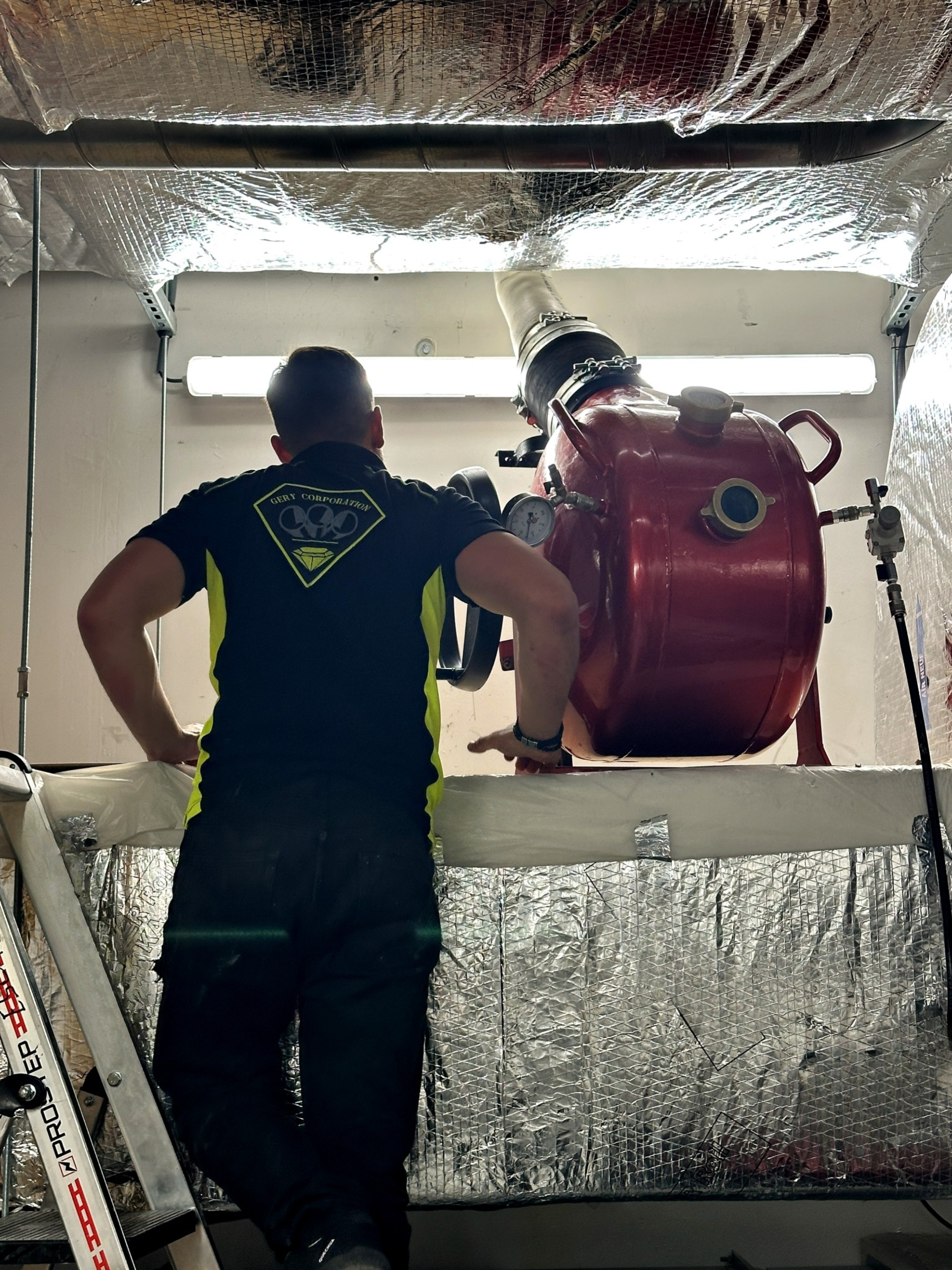 Technicien GERY CORPORATION utilisant un équipement de curage haute pression dans un espace confiné technique lors d'une intervention de chemisage
